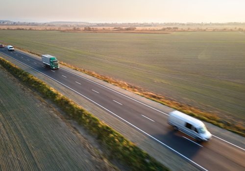 Aerial view of cargo trucks driving on highway hauling goods. Delivery transportation and logistics concept.