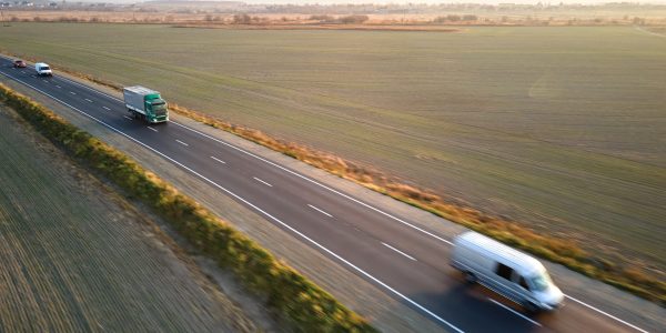 Aerial view of cargo trucks driving on highway hauling goods. Delivery transportation and logistics concept.